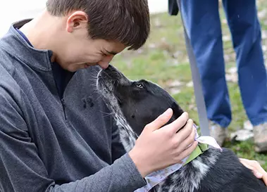 Dog giving a teen a kiss