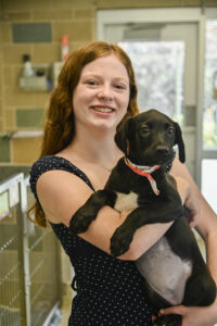 youth vol winners-3308 Evie standing in the dog adoptions area of the shelter, holding a black and white puppy